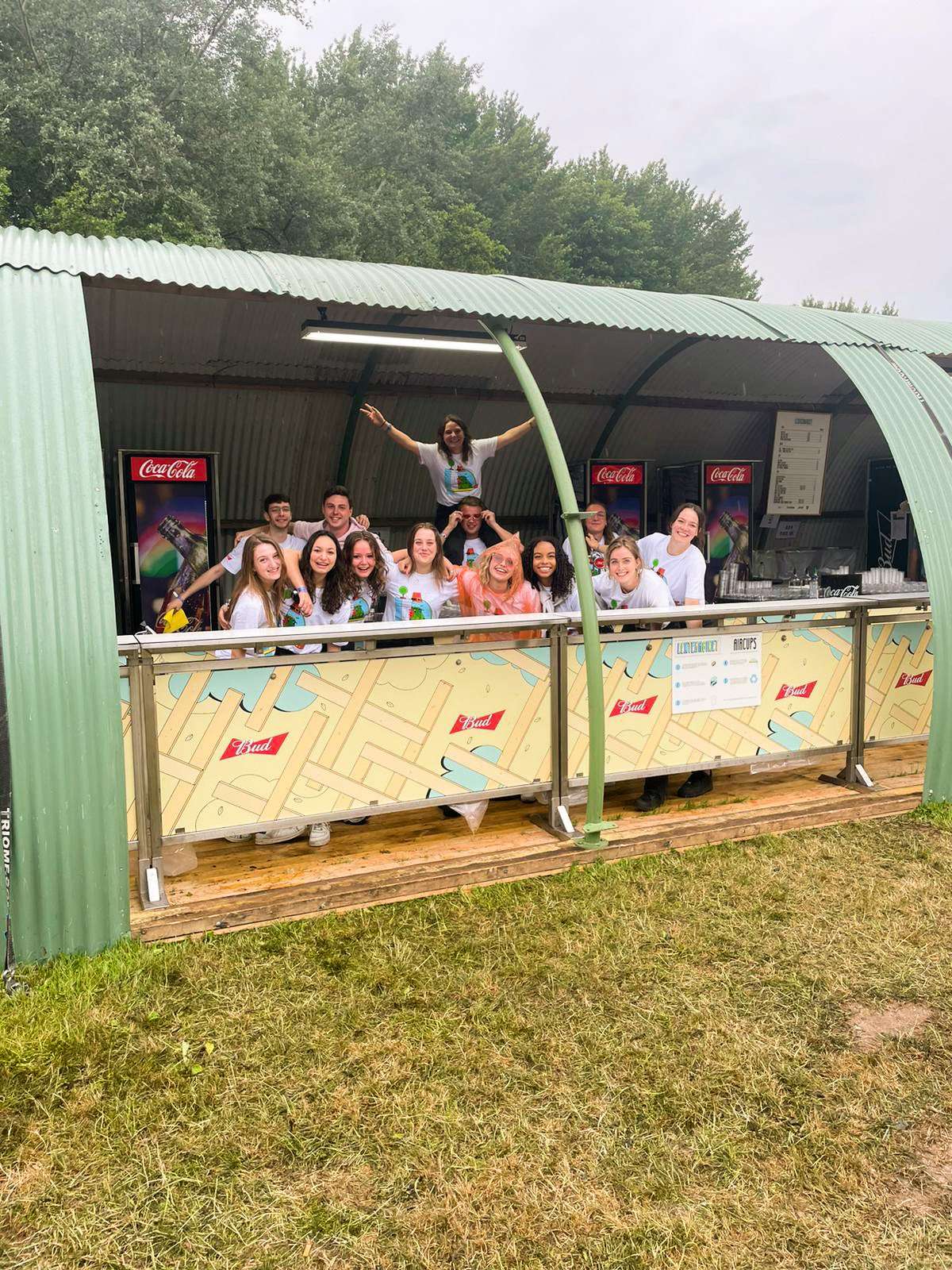 Large group of enthusiastic Skanna employees celebrating together at a festival bar, showing incredible team spirit and energy