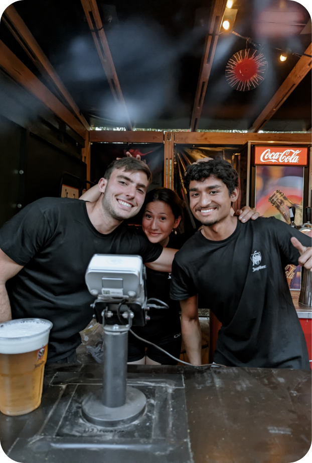 Three Skanna team members bonding together behind the bar in a cozy evening setting, showing close friendships
