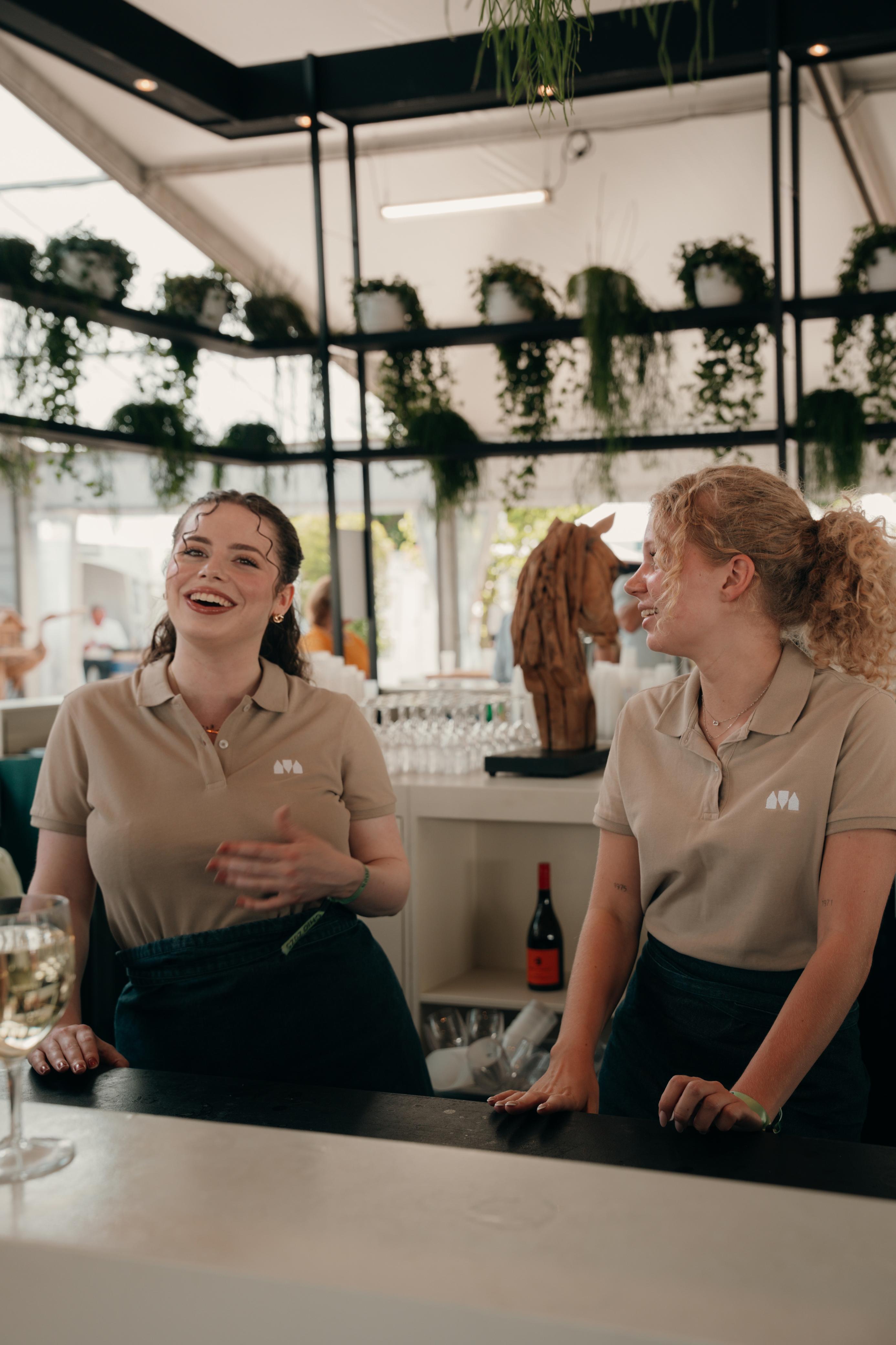 Two professional Skanna employees working happily behind the bar in a modern venue with botanical decor